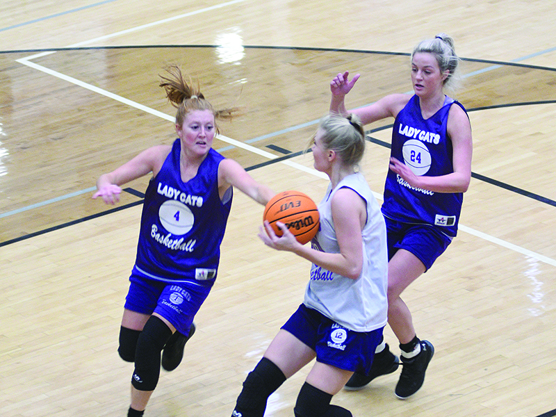 Gilmer Lady Cats Hope Colwell (4) and Emma Callihan (24) try to slow Lark Reece in transition during the Purple and White game. The trio will all receive significant varsity minutes this season.