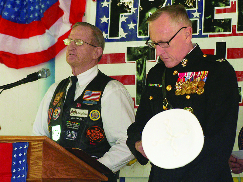 Marine Col. Michael Nunnally, right, bows his head in prayer as Fred McGill, chaplain for Ellijay’s American Legion Riders, gives an invocation during an honorary Veterans Day program held at the Lions Club Fairgrounds Wednesday, Nov. 11.