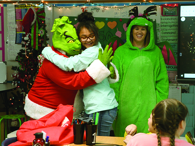 Fifth grader Ja’lan Garrett hugs the Grinch (Melanie Sanford), who brought along an ersatz reindeer, Hope Johnson, to distribute the books.