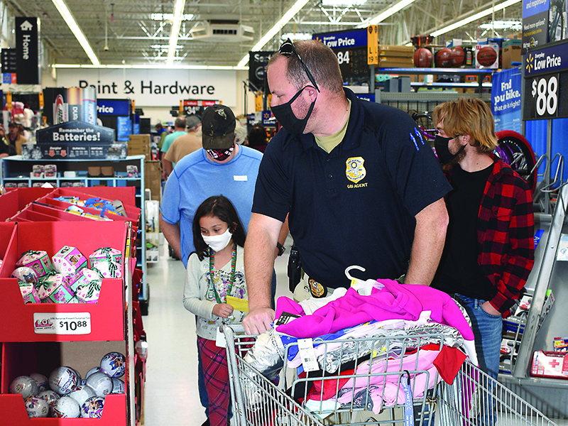 Agent Chris Minney, of the Georgia Bureau of Investigation, front, and volunteer Nate Grace, right, shop with a family at the East Ellijay Walmart on the first day of this year’s Shop With a Hero event.