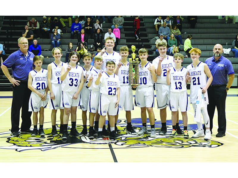CCMS seventh-grade basketball players and coaches gather around the Bobcats’ first-place league trophy last Friday.