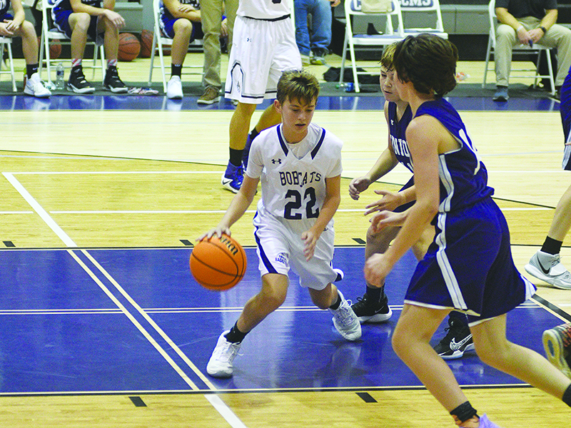 Eighth-grade Bobcat Haden West looks for room to maneuver between two defenders after collecting a defensive rebound.
