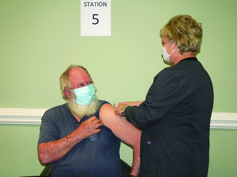 Eston Cantrell, left, rolls up his sleeve to receive the COVID-19 vaccine from Gilmer Health Department nurse Leigh Ann Dover at the Piedmont Community Center.