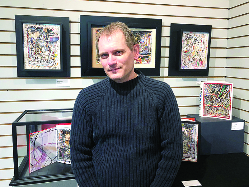 Book sculptor Ted Wray stands in front of a collection of his art work currently on display as part of a juried exhibit at the Gilmer Arts Gallery.