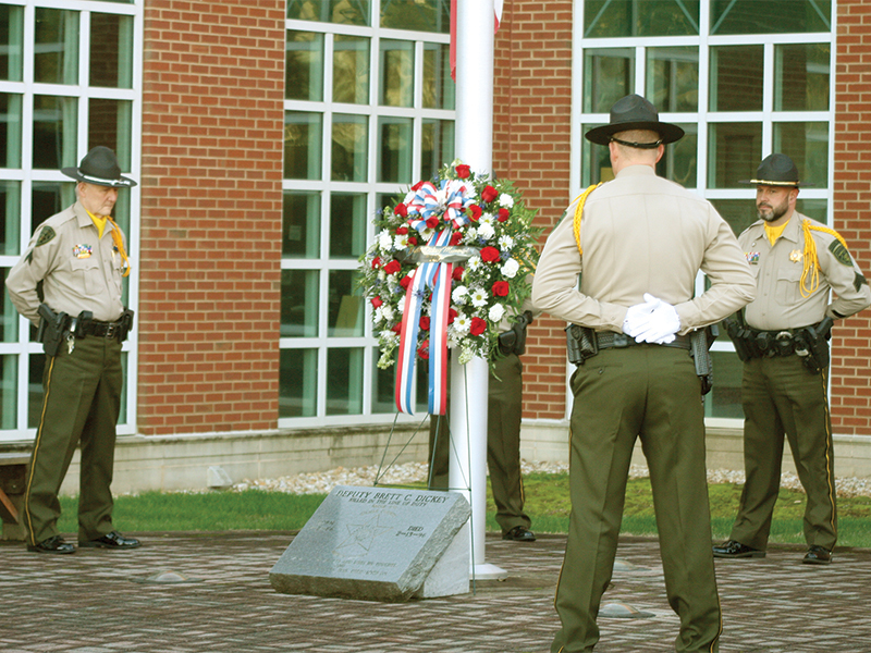 Honor guard members Cpl. Al Greenway, Deputy Ryan Scott and Sgt. Randy Beavers encircle a red, white and blue wreath placed at the memorial marker for Dickey outside the courthouse. 