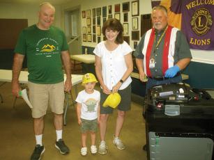On Election Day, voters Mike and Gina Putman, with grandson, Ezra McClure, are helped by poll worker Andy Broughton, right, at the Ellijay Northeast (Lions Club) polling place. 