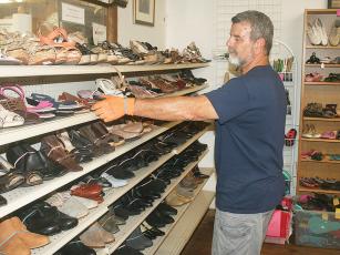 Volunteer Ray Costa re-arranges the shoe rack at Cartecay Thrift Store. 