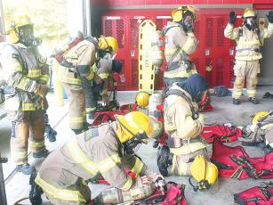 Participants in Gilmer Fire and Rescue’s noncertified recruit training program perform quick dress, in which they must put on protective bunker gear in two minutes or less. When recruits have fully suited up, they raise their hands to be checked by an instructor. 