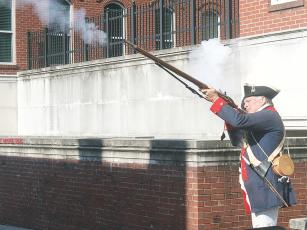 Mike Sutila, a member of the Sons of the American Revolution, fires a musket salute during a dedication ceremony for a commemorative America 250! marker outside the Gilmer County Courthouse.