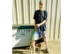 Gary Stanley and his dog, Gollum, are pictured next to a dropoff box for pet food donations at the Gilmer Community Food Pantry. 