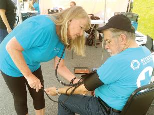 Volunteer and nurse Mary Young performs a blood pressure check during one of the mobile clinic’s previous stops at Faith, Hope and Charity Recycle Store. (Photo by Mark Millican)