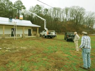 Ellijay Mayor Al Hoyle, left, and metalworker Tommy Cofield, right, look on as a cupola that Cofield built is placed atop the restroom building at Harrison Park last week. 