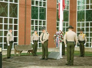 Gilmer County Sheriff’s Office personnel gather around the memorial marker for late Gilmer deputy Brett Dickey as a ceremony held to honor Dickey’s memory began Monday morning outside the courthouse. Dickey was killed in the line of duty on Feb. 13, 1996.