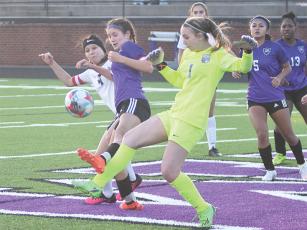 Gilmer’s Sophia Lykins battles for position with a West Hall defender and goalkeeper during last Friday’s match. Lykins scored a goal in each of the Cats’ matches last week.