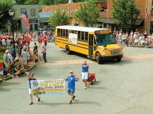 Members of the Gilmer County Optimist Club usher in this year’s Stuff the Bus school supply drive in the recent Fourth of July parade. (Photo by Robert Ferguson)