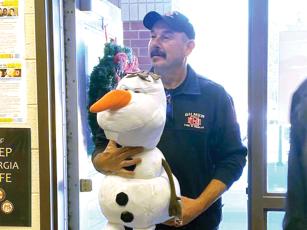 Eric Maddox carries an Olaf the Snowman doll during a past delivery of Christmas toys, which firefighters made to local schools. (Gilmer Fire and Rescue photo)