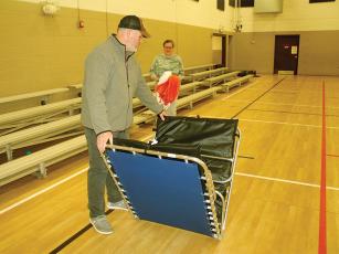Gilmer Warming Center volunteers Joey and Laura Lyles set up cots in the Civic Center gym, which is used as the warming center’s sleeping area. 