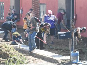 Members of the Gilmer High School band, chorus and drama classes clear grass and help level the ground for a pathway into the garden at Ellijay Elementary School that is being refurbished in memory of Noah West. (Photos by Robbie Bills)