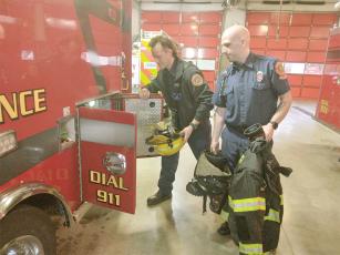 Gilmer County firefighter/EMT Jon Henderson, left, and firefighter/paramedic Phillip Boyle, right, retrieve some of their bunker gear from one of the fire department’s ambulances. 