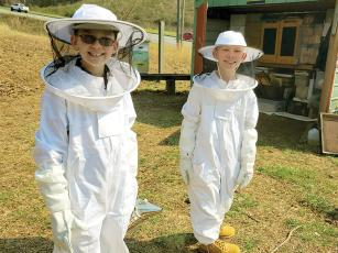 Brothers Attila and Vajc Atkinson wear their protective beekeeping gear during a recent mentoring session at the apiary maintained by the Beekeepers of Gilmer County.  
